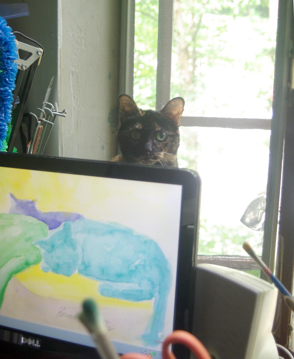 tortoiseshell cat behind computer monitor