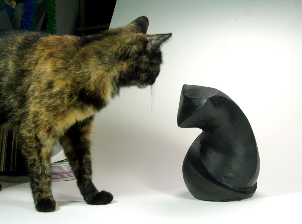 tortie cat with sculpture