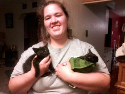 woman holding two black kittens