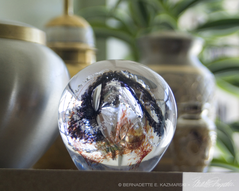 Cremains incorporated into a handmade glass ball along with a variety of urns.