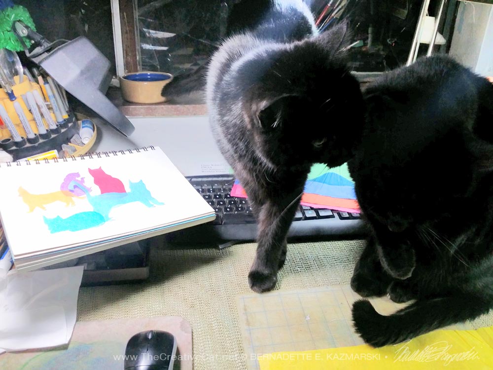black cats on drafting table with artwork