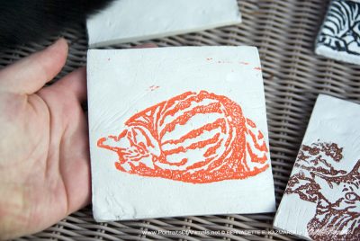 Air-dry clay tile, "Fawnball" in orange.